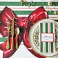 Christmas-themed place setting with red bow, gold cutlery, and holly design on a striped tablecloth.