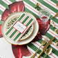 Christmas-themed table setting with red and green striped tablecloth, gold cutlery, and decorative name card.