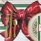 Christmas-themed place setting with gold cutlery, a red bow, and a striped background.