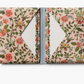 Floral-patterned notebook with a blue strap on a white background