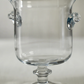 Clear glass goblet with decorative handles on a light gray background