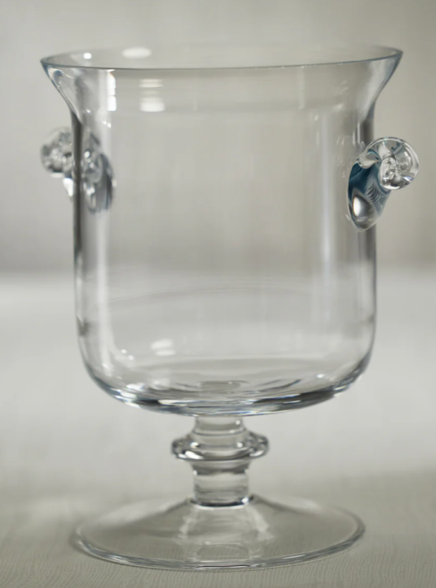 Clear glass goblet with decorative handles on a light gray background