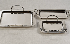 Set of three silver trays with handles on a light gray background