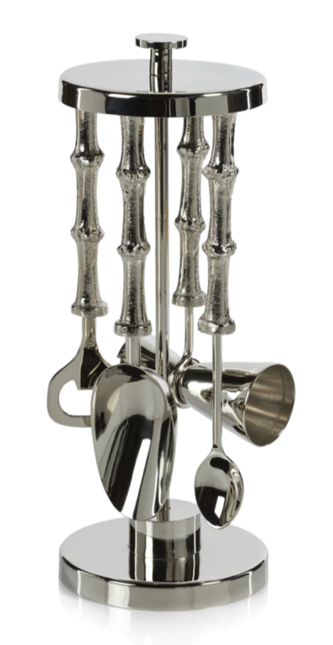 Set of silver kitchen utensils on a cylindrical stand with bamboo-like design on a white background