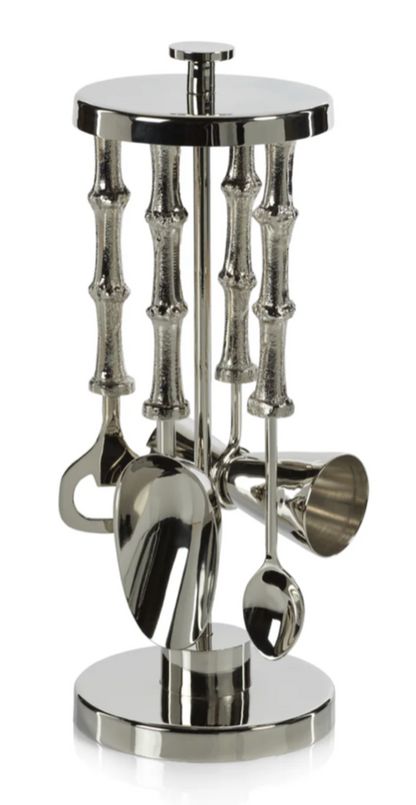 Set of silver kitchen utensils on a cylindrical stand with bamboo-like design on a white background