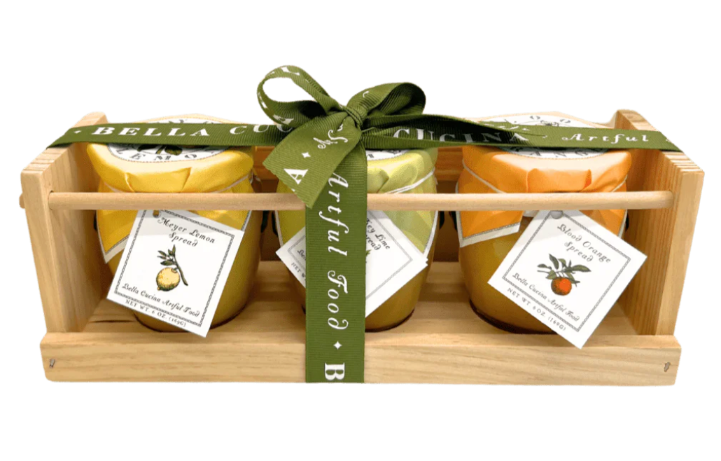 Three jars of Bella Coda lemon curd in a wooden crate with a green ribbon.
