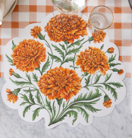 Floral placemat with orange marigold flowers on a checkered tablecloth.