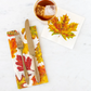 Napkin with autumn leaf design featuring a fork, knife, and cup on a white background