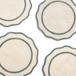 Set of four round woven coasters with scalloped edge on a white background