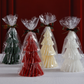 Four tree-shaped candies in red, green, white, and yellow, each wrapped in clear cellophane with decorative ribbons against a red background.