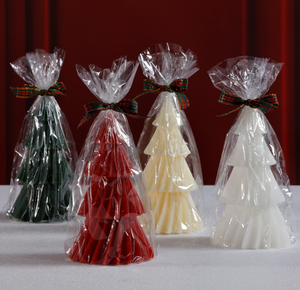 Four tree-shaped candies in red, green, white, and yellow, each wrapped in clear cellophane with decorative ribbons against a red background.