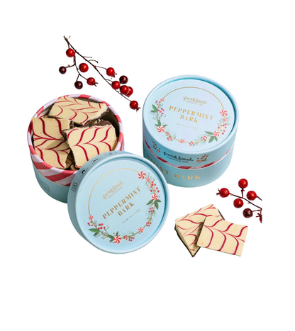 Three round blue tins with peppermint bark on a white background