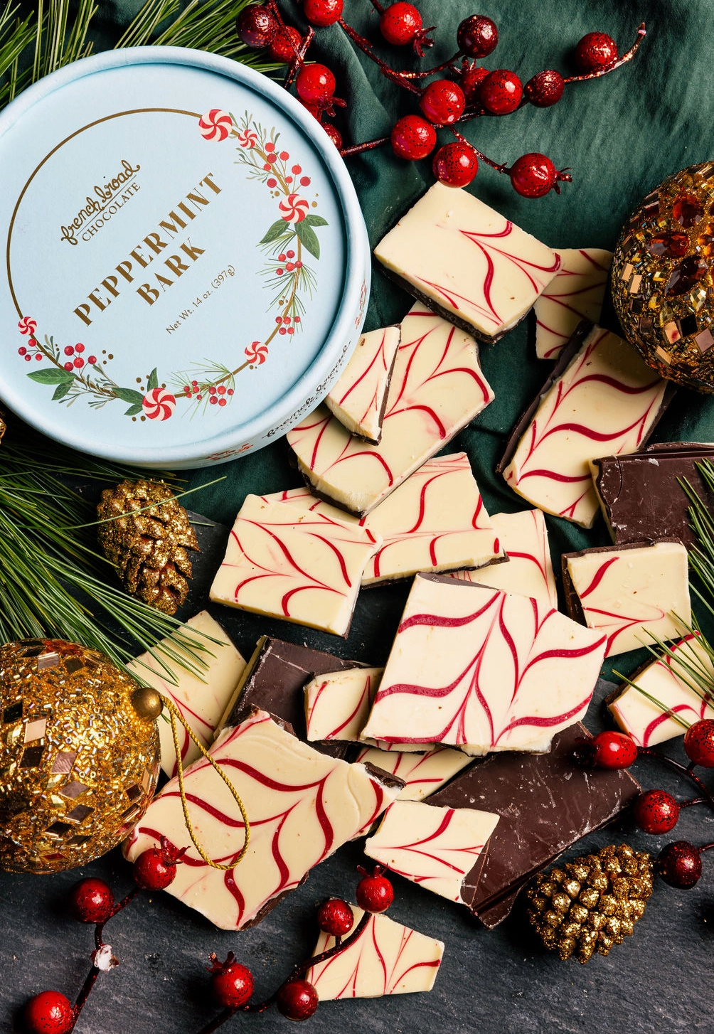Peppermint bark with a decorative tin and holiday elements on a dark surface