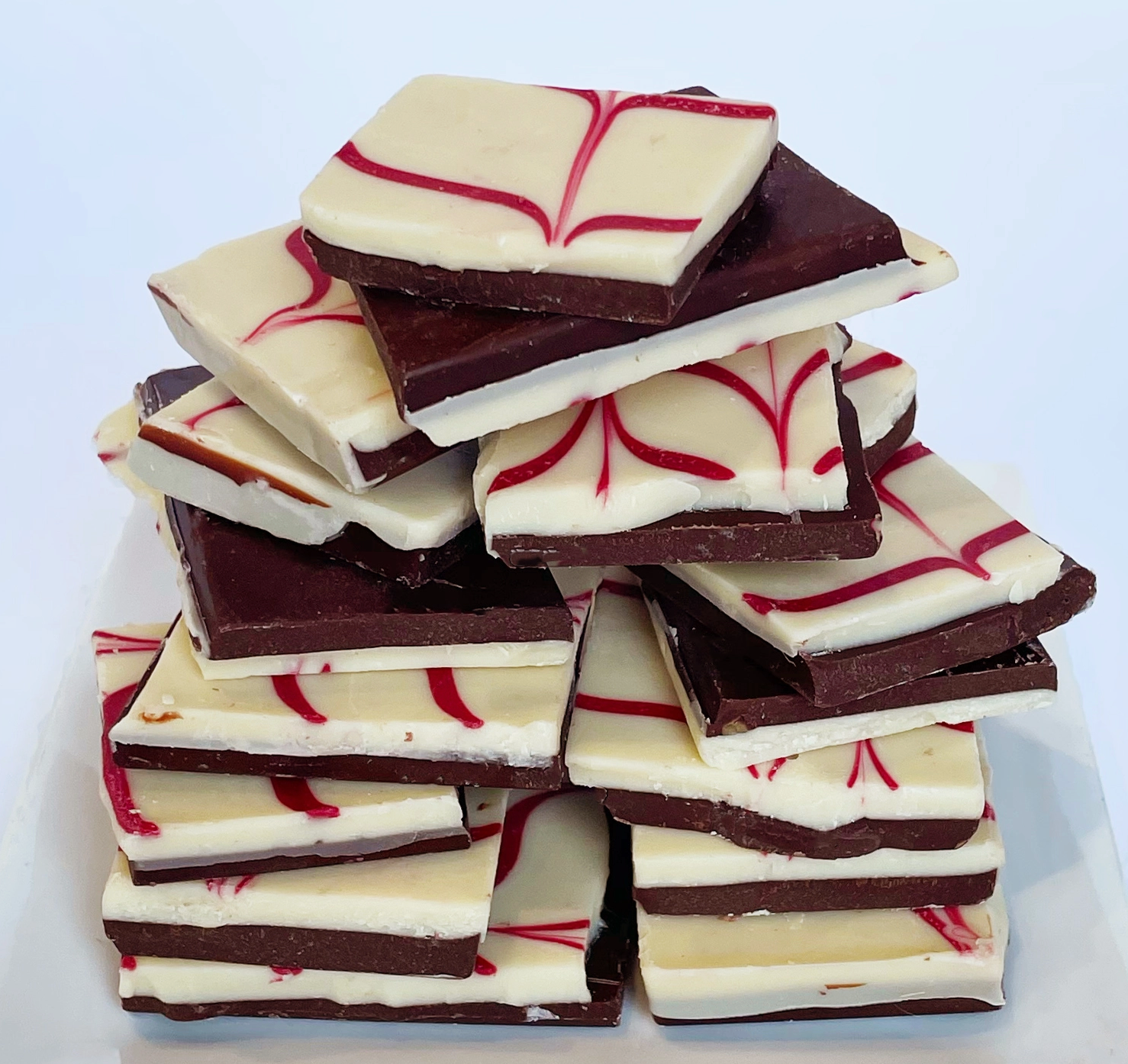 Stack of chocolate and white candy bars with red swirls on a white background