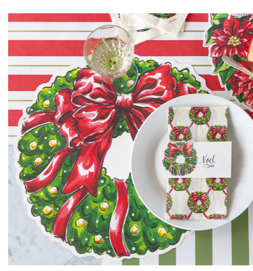 Christmas-themed table setting with a plate, napkin, and decorative elements on a striped tablecloth.