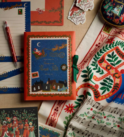 Decorative book with festive design on a textured surface with stationery items.