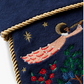 Embroidered design of a person on a crescent moon with stars and flowers on a dark blue background.