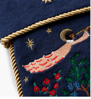 Embroidered design of a person on a crescent moon with stars and flowers on a dark blue background.