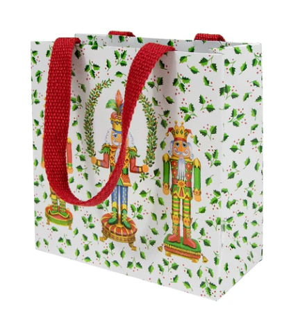 Gift bag with nutcracker design and red handles on a white background