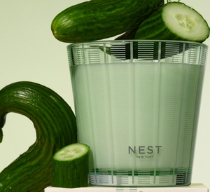 Cucumber slices and a glass of water with 'NEST New York' branding on a light background