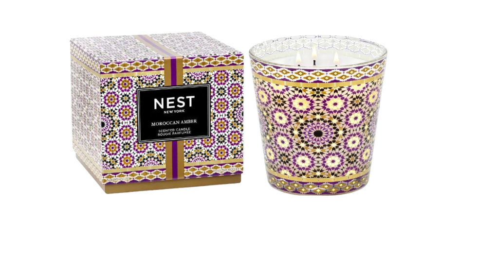 Decorative candle with patterned design and matching packaging on a white background