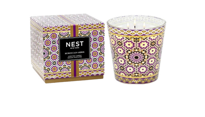 Decorative candle with patterned design and matching packaging on a white background