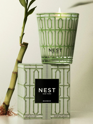 NEST New York candle with decorative packaging and bamboo plant on a light background