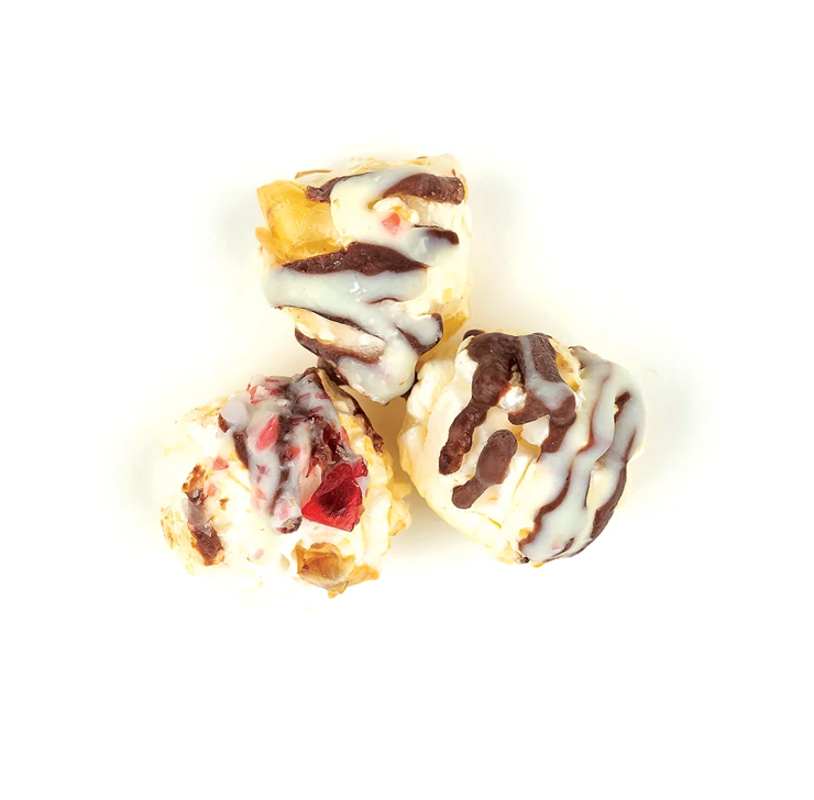 Three dessert items with chocolate and white drizzle on a white background