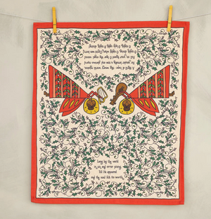 Decorative tea towel with musical instruments and text, framed by red border and holly leaves.