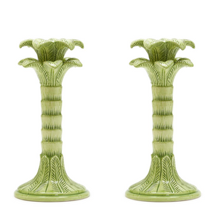 Two green ceramic candle holders with decorative designs on a white background