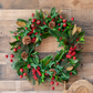 Christmas wreath with green leaves, red berries, and pinecones on a wooden background