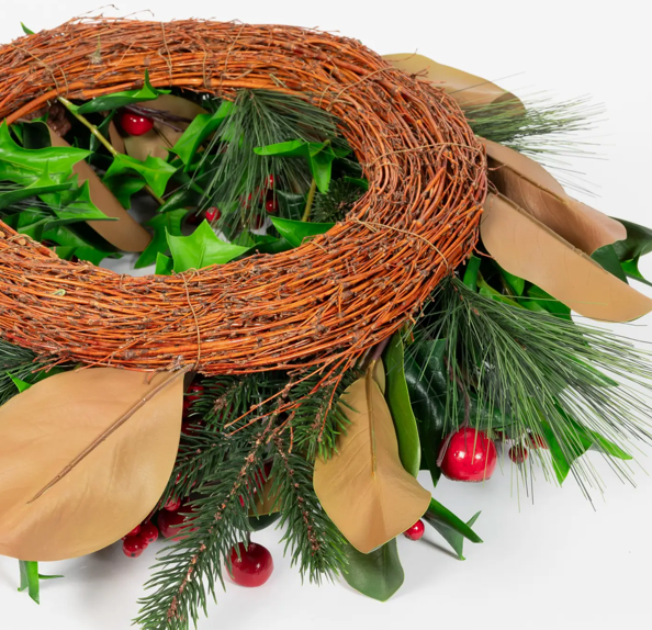Decorative wreath with greenery, red berries, and brown leaves on a white background