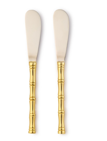 Two cream-colored butter knives with gold bamboo handles on a white background