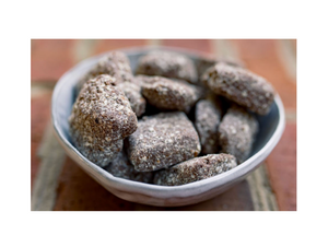 Bowl of powdered sugar-coated treats on a wooden surface