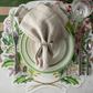 Christmas-themed place setting with holly design on placemat, white plate, and beige napkin.