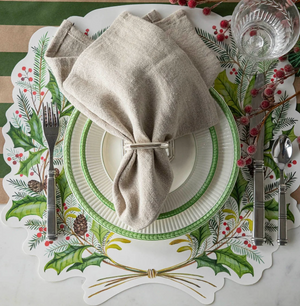 Christmas-themed place setting with holly design on placemat, white plate, and beige napkin.
