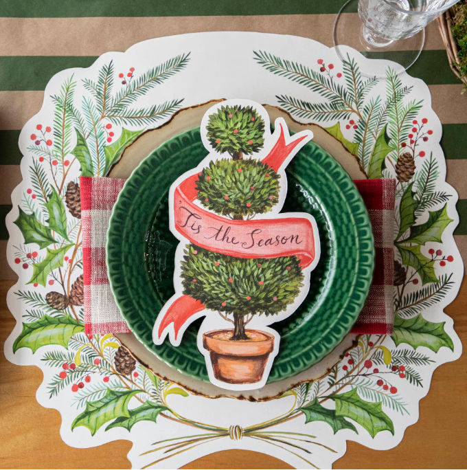 Christmas-themed place setting with a decorative plate and placemat on a wooden table.