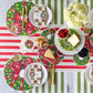 Christmas-themed table setting with wreath placemats and striped tablecloth.