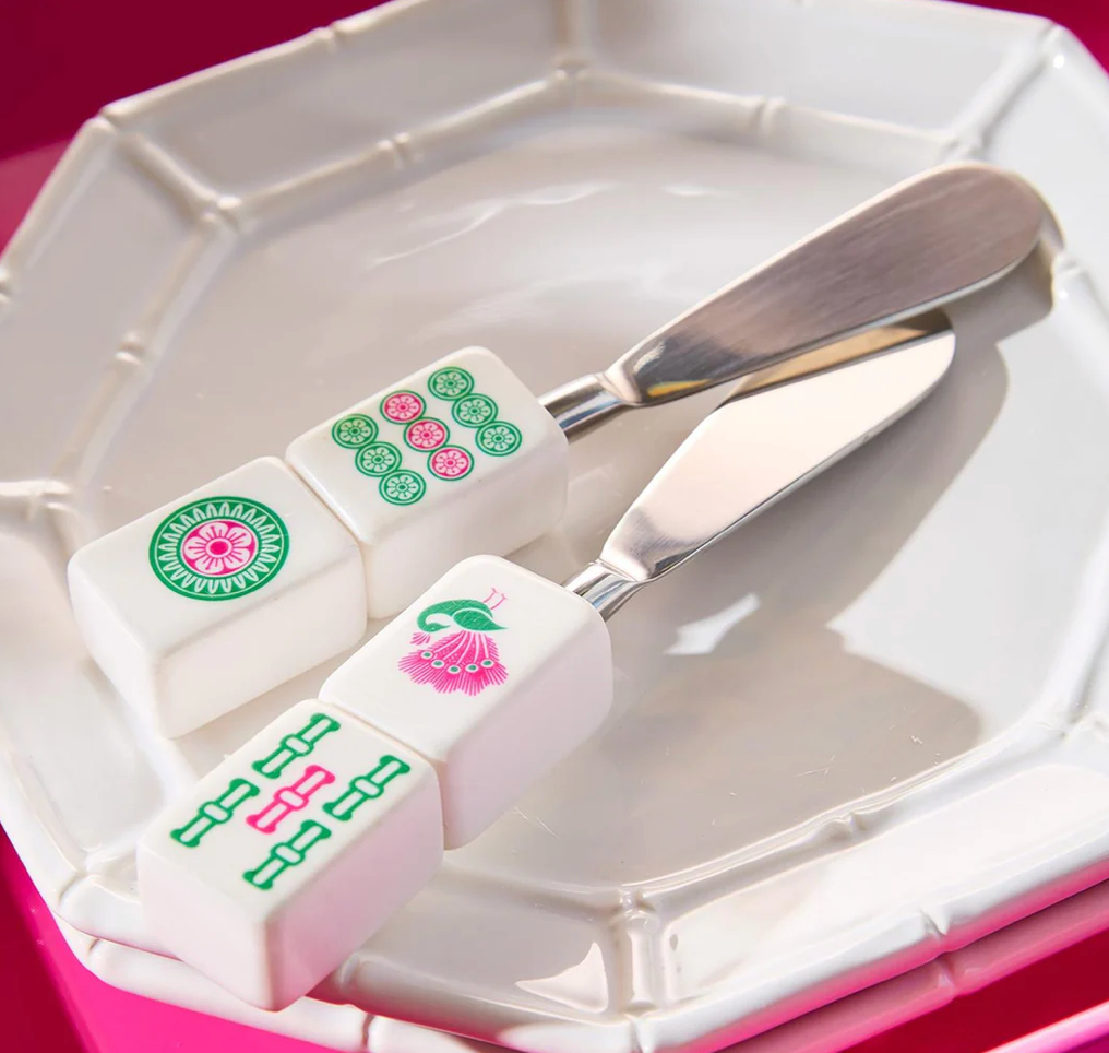 Butter knife with decorative handles resembling Chinese mahjong tiles on a white plate.